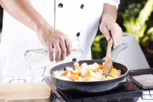 Koch bereitet Essen in Induktionspfanne zu
