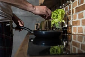 Mann schlägt Ei in Pfanne auf
