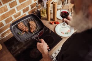 Mann brät Steaks in Bratpfanne