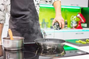 Mann gießt Öl in Pfanne